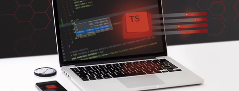 Silver MacBook on desk displaying TypeScript code with red "TS" highlight, beside smartphone and watch.